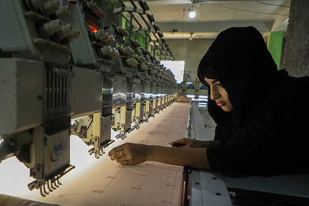 A woman works at an embroidery machine in a textile factory at Kamrangirchar.