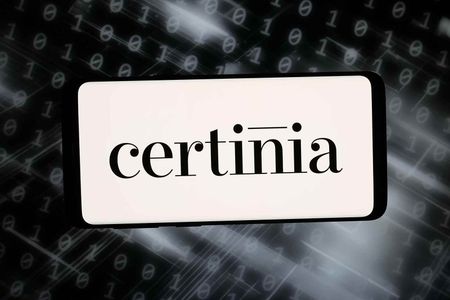 In this photo illustration, the logo of US ERP software company Certinia Inc. is displayed on a smartphone in front of abstract background on computer screen.