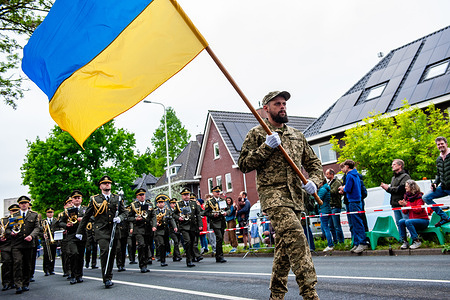 A Ukrainian soldier is carrying the flag of his country during the parade. The Liberation Parade reunites veterans and military successors to pay tribute to all those who gave their lives during WWII and to international military cooperation. Like in previous years, Canadian and English WWII veterans led the parade.