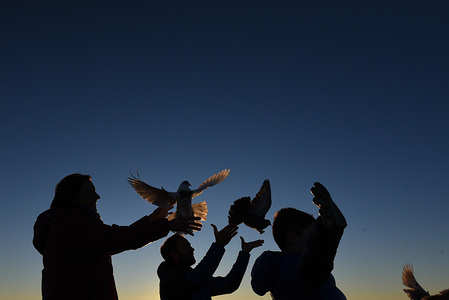 Silhouette of people seen releasing homing pigeons to welcome the arrival of the New Year at sunset in Almazán, north of Spain.