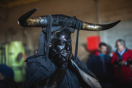 A Reveller is seen dressing up with oil and soot during the Devils of Luzon Carnival. Hundreds of people turn out to celebrate the ancient tradition of the Festival of Devils and Masked Figures. People dress like devils with bull horns, cowbells and paint thei body with black oil and soot. Revellers wear white masks. The tradition goes back to the 14th century.
