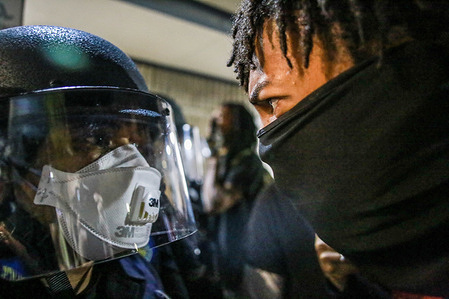 A protester stands face to face with a police officer during the demonstration.
A peaceful protest, spurred by the death of George Floyd, turned violent as protesters clashed with police, throwing rocks and bottles at police while police responded by shooting pepper spray balls at protesters and using flash bang grenades to disperse the crowd.