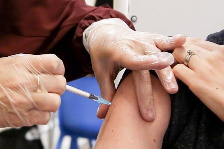 NHS health worker administers Pfizer-BioNTech Covid-19 vaccine to a woman at a vaccination centre in London.