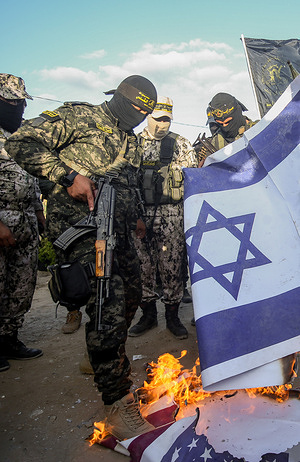 Islamic Jihad activists seen burning the Israel and United States of America flags during an Anti-Israel and USA military parade in the south of the Gaza Strip.