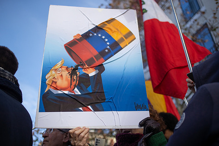 A protester holds a banner with a caricature of Donald Trump drinking Venezuelan oil. During a rally organized by leftist groups in front of the US Embassy in Madrid to condemn the attacks carried out by the United States in Caracas in the early hours of January 3rd and the illegal arrest of President Nicolás Maduro and his transfer to a prison in New York along with his wife.