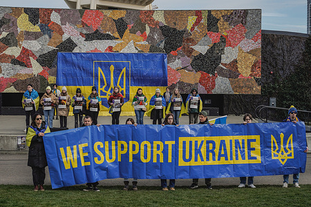 A group of democracy protesters holding Ukrainian flags and “We support Ukraine" as they march through the Seattle Center. Democracy protesters gathered at Seattle Center to mark the one-year anniversary of Russia's invasion of Ukraine. The event, organized by local Ukrainian-American groups, drew participants from across the region that came together to demand an end to Russian aggression and a return to democratic rule in Ukraine.