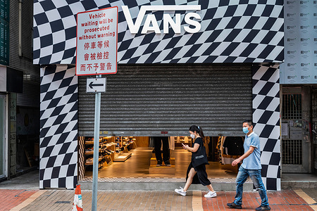 Pedestrians walk past the American multinational sports clothing brand owned by VF Corporation, Vans, store in Hong Kong.