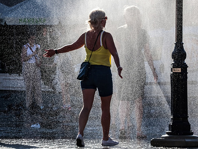 A woman cools down under the water sprinkler set up in Main Market Square. Most parts of Europe are experiencing a heat wave with temperatures expected to exceed 37 degrees Celsius tomorrow.
