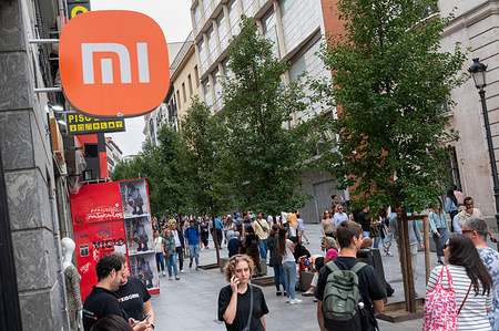 Pedestrians walk past the Chinese multinational technology and electronics brand Xiaomi's flagship store and logo in Spain.