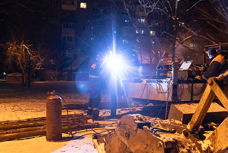 Utility workers are seen performing welding repairs outdoors at night in snowy conditions near residential buildings. Winter in Kyiv has become a true test of endurance as regular mass attacks by Russia on energy infrastructure have plunged the city into prolonged blackouts. Amidst extreme frosts and power outages, the capital has transformed into a fortress of resilience, where life is sustained by the selflessness of thousands. Special heating points in tents have been deployed across the streets, serving as islands of warmth where residents can charge gadgets, drink hot tea, and find refuge from the cold. The true heroes of this time are the utility and heating network repair teams, who work around the clock despite icy winds and the danger of new strikes to fix heating and power supply failures. Despite the enemy's attempts to freeze the metropolis, the unity of its citizens and the professionalism of municipal services allow Kyiv to stand firm.