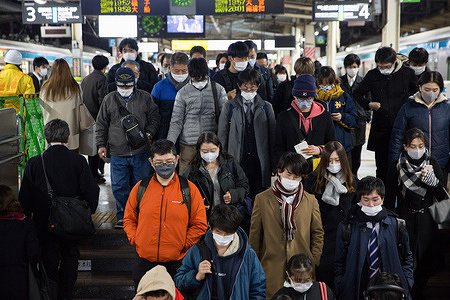 Passengers wearing facemasks at Yokohama Station descend stairs from the platform to enter the main Hall of the station.