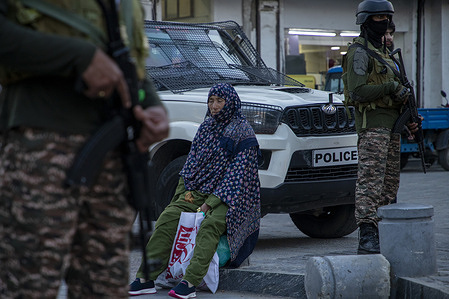 A woman sits as Indian paramilitary soldiers stand alert in a street of Srinagar, the summer capital of Jammu and Kashmir. India launched "Operation Sindoor", striking nine sites in Pakistan. Pakistan reports missile attacks on six locations, killing at least eight and injuring 35, calling it an "act of war." Two unidentified jets crashed in Jammu and Kashmir shortly after the strikes. Pakistan says the death toll has reached 26 from Indian attacks, with 10 more killed in Pakistani shelling along the border.