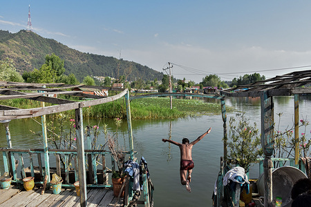 A Kashmiri boy dives into the world-famous Dal Lake during a hot summer day in Srinagar. Severe heat waves sweeps across Kashmir valley, pushing temperatures to unprecedented highs in several locations. Weatherman has advised residents to avoid outdoor activities during peak hours, stay hydrated, and take necessary precautions to cope with the ongoing heatwave.