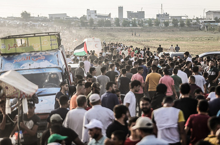 Palestinian protesters hurry away as tear gas canisters shot by Israeli security forces from across the Gaza border fall, during the demonstration by the border fence with Israel, east of Gaza City, denouncing the Israeli siege of the Palestinian strip, Saturday marks the 52nd anniversary of an attempt to burn the Al Aqsa Mosque at a time when new and dangerous Israeli violations threaten the buildings and sanctities through excavations carried out by the Israeli occupation authorities underneath the mosque's walls.