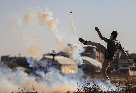 A Palestinian demonstrator kicks back a tear gas canister with his foot during confrontations with Israeli security forces along the border with Israel, east of Khan Yunis, in the southern Gaza Strip.
