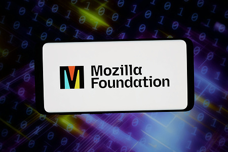 In this photo illustration, the logo of open-source organisation Mozilla Foundation seen displayed on a smartphone in front of abstract background on a computer screen.