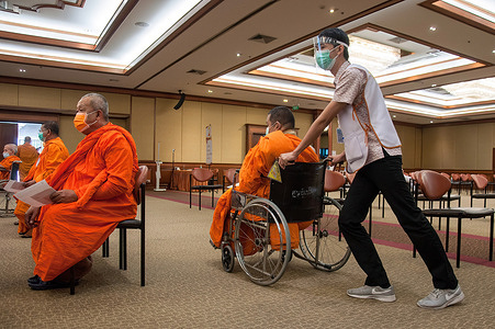 A health worker pushes a wheelchair for a Thai Buddhist monk during a vaccination drive against the COVID-19 coronavirus pandemic at the Priest Hospital in Bangkok.