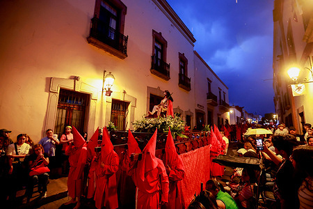 Penitents and members of a brotherhood seen walking during the procession of silence. The Procession of Silence is a public manifestation of mourning, respect, and repentance that began in Querétaro in 1966. Wearing robes of black, red, purple, white, and green, participants carried crosses and chains in a silent procession through the streets of the historic center to accompany the Virgin Mary in her hours of sorrow for the death of her son, Jesus Christ.