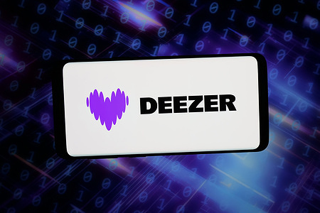 In this photo illustration, the logo of French music streaming company Deezer S.A. is displayed on a smartphone in front of abstract background on computer screen.