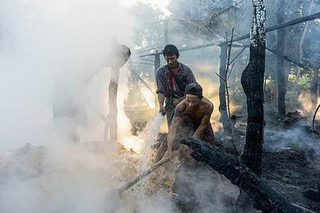 Villagers extinguish a fire that engulfed a house after an airstrike carried out by the Myanmar military. At least three houses were set ablaze, six people were injured, and livestock were lost after the military junta launched five airstrikes across three villages in a single day. The Myanmar military junta frequently carries out airstrikes targeting civilians, causing deaths, injuries, and the loss of homes and livestock.