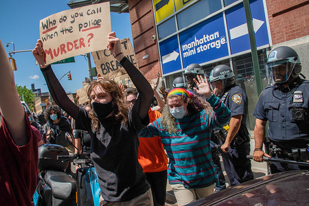 A protester marching while carrying a placard passed police officers during a demonstration.Several protests around US have been spurred by the death of George Floyd, in most cases turning into violent clashes with police.