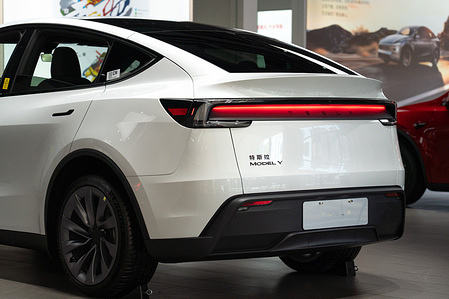 The rear section of a white Tesla Model Y electric crossover displayed inside a Tesla showroom. The Model Y remains one of the top-selling luxury electric vehicles in the domestic Chinese automotive market.