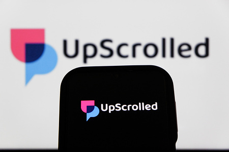In this photo illustration, The UpScrolled logo is displayed on a mobile phone and in the background.