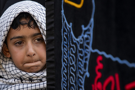 A Kashmiri Shiite Muslim boy watches as mourners take part in a religious procession marking Ashura, on the 10th day of the Islamic month of Muharram, in Srinagar, the main city in Indian administered Kashmir. Ashura, the 10th day of Muharram, commemorates the martyrdom of Imam Hussain, the grandson of the Prophet Muhammad, who was killed along with members of his family and companions in the Battle of Karbala in present day Iraq in 680 AD.