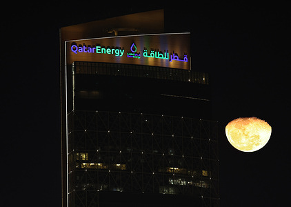 The moon appears next to the tower complex of Qatar Energy's headquarters in West Bay.
