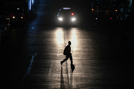 A man crosses the street at Khlong Toei market area, Bangkok.