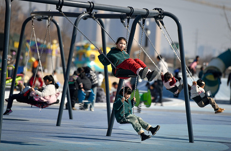 Several little girls play on swings in the park. Data from China's National Bureau of Statistics (NBS) showed that the country's population at the end of 2024 was 140,828,000 and in 2023 was 1,390,000.