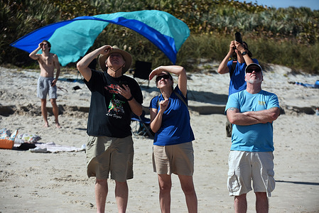 People watch from Canaveral National Seashore as a SpaceX Falcon 9 rocket launches from pad 39A at the Kennedy Space Center in Cape Canaveral, Florida. 
The rocket is carrying 49 Starlink internet satellites for a broadband network.