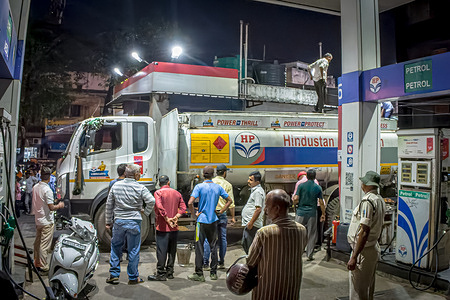 A petrol tanker replenishes fuel supplies under the supervision of police and station staff as motorcyclists wait in long queues amid widespread panic buying. Despite official assurances, soaring global crude prices fueled by Middle East tensions have driven domestic inflation, prompting the Reserve Bank of India (India's central bank) to hike interest rates. Prime Minister Narendra Modi has urged citizens to reduce fuel consumption to protect national reserves, as critics highlight his continued international travel during the austerity push.