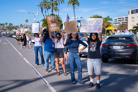 Demonstrators hold handmade signs during a protest opposing recent U.S. and Israeli military strikes on Iran. Messages on the signs include “Stop the War Machine,” “No War with Iran,” and “Peace & Diplomacy Were Possible but U.S. & Israel Chose War,” as participants line the street and engage with passing traffic. Around 200 demonstrators gather at Waterfront Park in San Diego on February 28, 2026, to protest recent U.S. and Israeli military strikes on Iran. The rally features multiple speakers addressing the crowd and calling for an end to military escalation and renewed diplomatic efforts. No visible police presence is observed at the event.