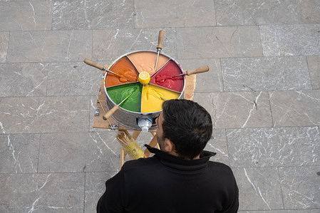 A Turkish street vendor selling brightly colored Macum, a popular soft, sweet, and colorful Turkish toffee paste.