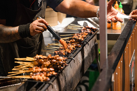 Kitchen staff members prepare skewers, cooked over hot coals during the event. ​A vibrant celebration of Asian street food, culture, and music, the Hawker 88 Night Market at Melbourne's Queen Victoria Market comes alive with colorful stalls, sizzling dishes, and lively entertainment.