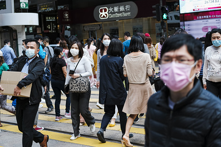People with surgical face masks cross the street in Central, following the corona threat.
The new corona virus still spreads worldwide, as World Health Organisation warns. The deadly corona virus (known as COVID-19) has increased rapidly in parts of Asia, Europe and the Middle East in recent days.