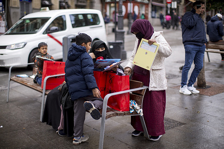 Mothers and children open gifts from the Three Kings during the distribution of toys to children in the multicultural Lavapies district, in the center of Madrid, at the traditional Three Kings Day celebration organized by the La Corrala Neighborhood Association.