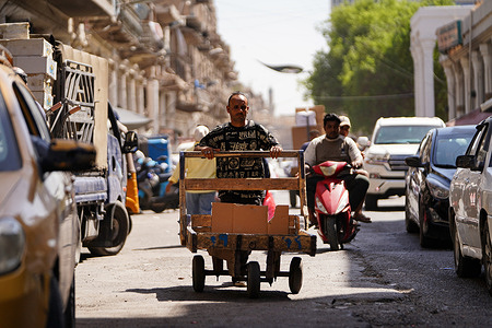An Iraqi porter pushes a cart on Al-Rashid Street in central Baghdad.
