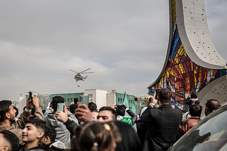 A man drops from a helicopter in front of a crowd at Umayyad Square in Damascus. Many Syrians celebrated the first anniversary of the fall of the Assad regime on December 8, 2025, as "liberation day".