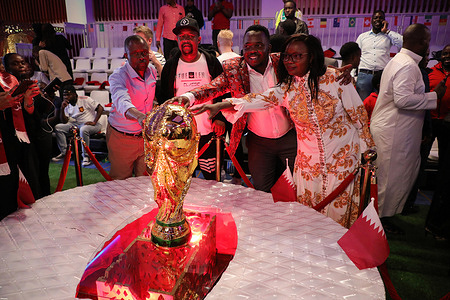 Football fans take a photo with the replica of the world cup trophy during the screening of the World Cup Qatar 2022 final football match between Argentina and France by the Qatar Embassy at Movenpick Hotel in Nairobi.