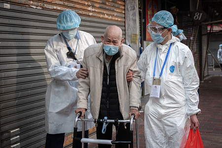 Health workers help an elderly resident returning home in an area under lockdown to contain the spread of Covid-19 outbreak.More than 3,000 police officers and health workers have been deployed for an unprecedented screening operation in Jordan district with about 200 buildings after coronavirus cases being detected.