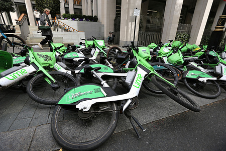 Pedestrian seen passing behind a pile of Lime bikes that are blocking the pavement. Abandoned Lime bikes block the pavement in Arundel Street in London. They are frequently being accused of causing obstructions on London’s pavements especially for strollers or those with disabilities with local councils increasingly imposing strict on the spot fines and implementing bay only parking. There is a system for members of the public to report bikes that are causing an obstruction.