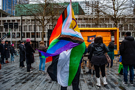A man is seen holding a Palestinian flag and an LGBTQ pride flag on his back during the rally. Feminist group Dolle Mina organized a protest in solidarity with women affected by gender-based violence, but also against human rights violations everywhere in the world. The Netherlands is home to around two hundred nationalities. With this protest, the Dolle Minas wants to unite everybody to stay stronger against injustice.