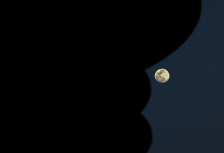 The moon appears as a full moon in the sky over Doha, the capital of Qatar.