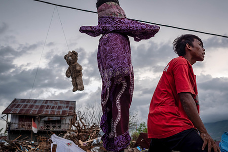 A resident seen next to a hanging teddy bear at the Lere Village after the earthquake and tsunami.
A deadly earthquake measuring 7.5 magnitude and the tsunami wave caused by it has destroyed the city of Palu and much of the area in Central Sulawesi. According to the officials, death toll from devastating quake and tsunami rises to 2088, around 5000 people in hospitals are seriously injured and some 62,000 people have been displaced.
