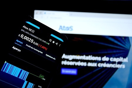 In this photo illustration, the stock price of the French digital company Atos is displayed on a phone, with its official website visible in the background.