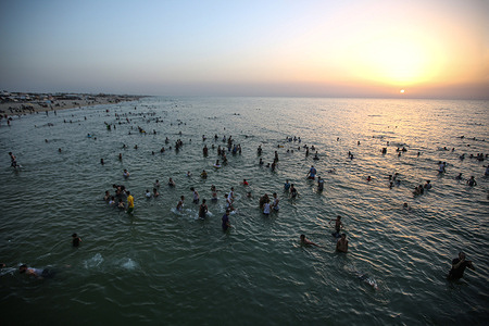 Palestinians swim in the Mediterranean Sea during a hot day with temperatures rising in Khan Yunis, in the southern Gaza Strip