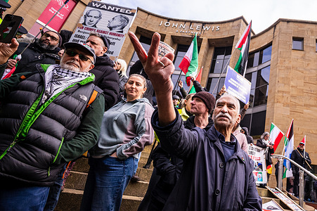 An anti-war protester gestures towards the pro-conflict demonstration. On the afternoon of the 28th of February members of the pro-monarchy Iranian diaspora in Scotland gather at the Buchanan Street steps in Glasgow to celebrate the attacks on Iran by Israel and the United States of America, earlier that morning. Demonstrators gather with flags, placards, and effigies and chant pro-monarchy and anti-Islamic Republic slogans. At the same time, anti-war demonstrators gather to counter-protest the attacks of Iran.