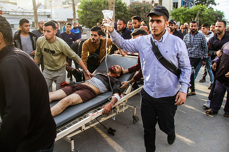 (EDITORS NOTE: Image contains graphic content)
Palestinians carry a man injured in the Israeli raid on a stretcher bed, in Gaza City.